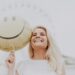 Cheerful woman holding a smiley balloon outdoors on a sunny day, exuding happiness and positivity.