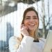 Confident businesswoman using her tablet and phone, smiling outdoors in sunlight.